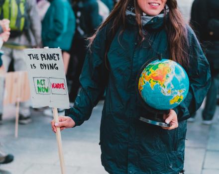 Warsaw, Poland - Oct 11, 2021: Women (sic) holds a globe of earth and a banner with phrase " The planet is dying. Act now. Ignore. Choose. Environment. Nature. Protest. Crowd. Street. Agreement (photo by Andrii Koval, available in iStockPhotos)