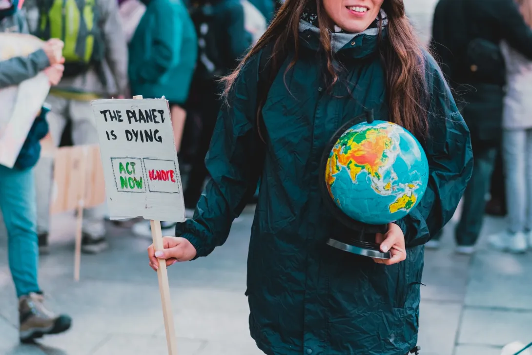 Warsaw, Poland - Oct 11, 2021: Women (sic) holds a globe of earth and a banner with phrase " The planet is dying. Act now. Ignore. Choose. Environment. Nature. Protest. Crowd. Street. Agreement (photo by Andrii Koval, available in iStockPhotos)
